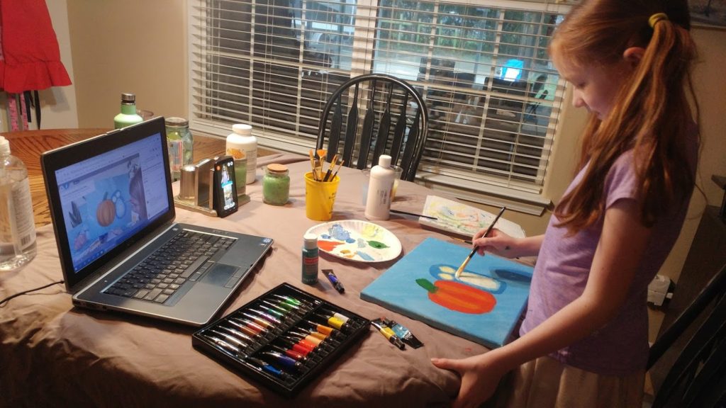 Granddaughter painting with grandmother using computer
